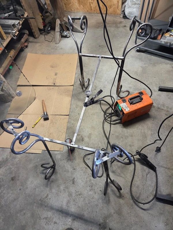 Piètement de table en fer forgé à volutes en cours de soudure à l’atelier